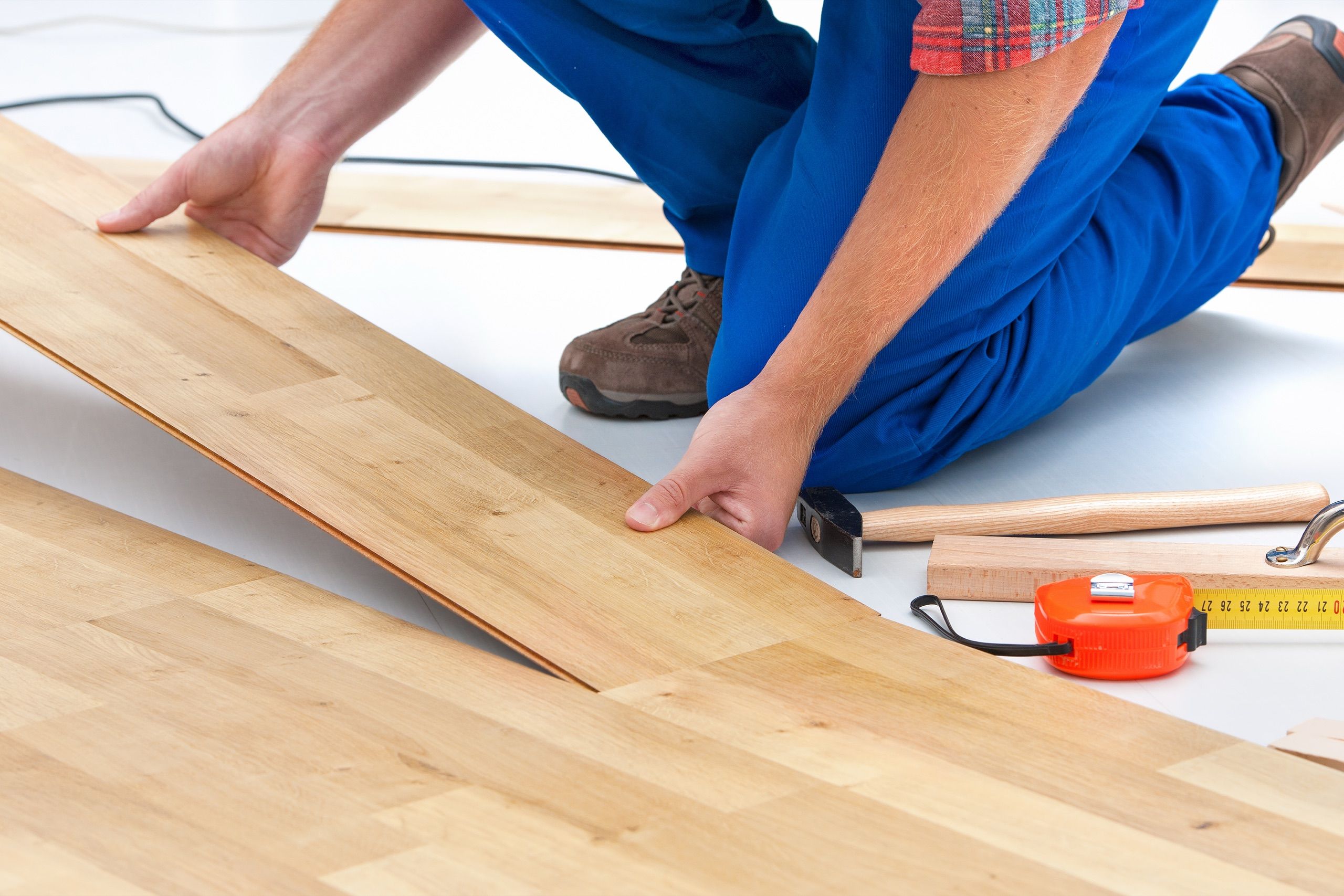 Handwerker verlegt helle Laminatdielen auf vorbereitetem Untergrund